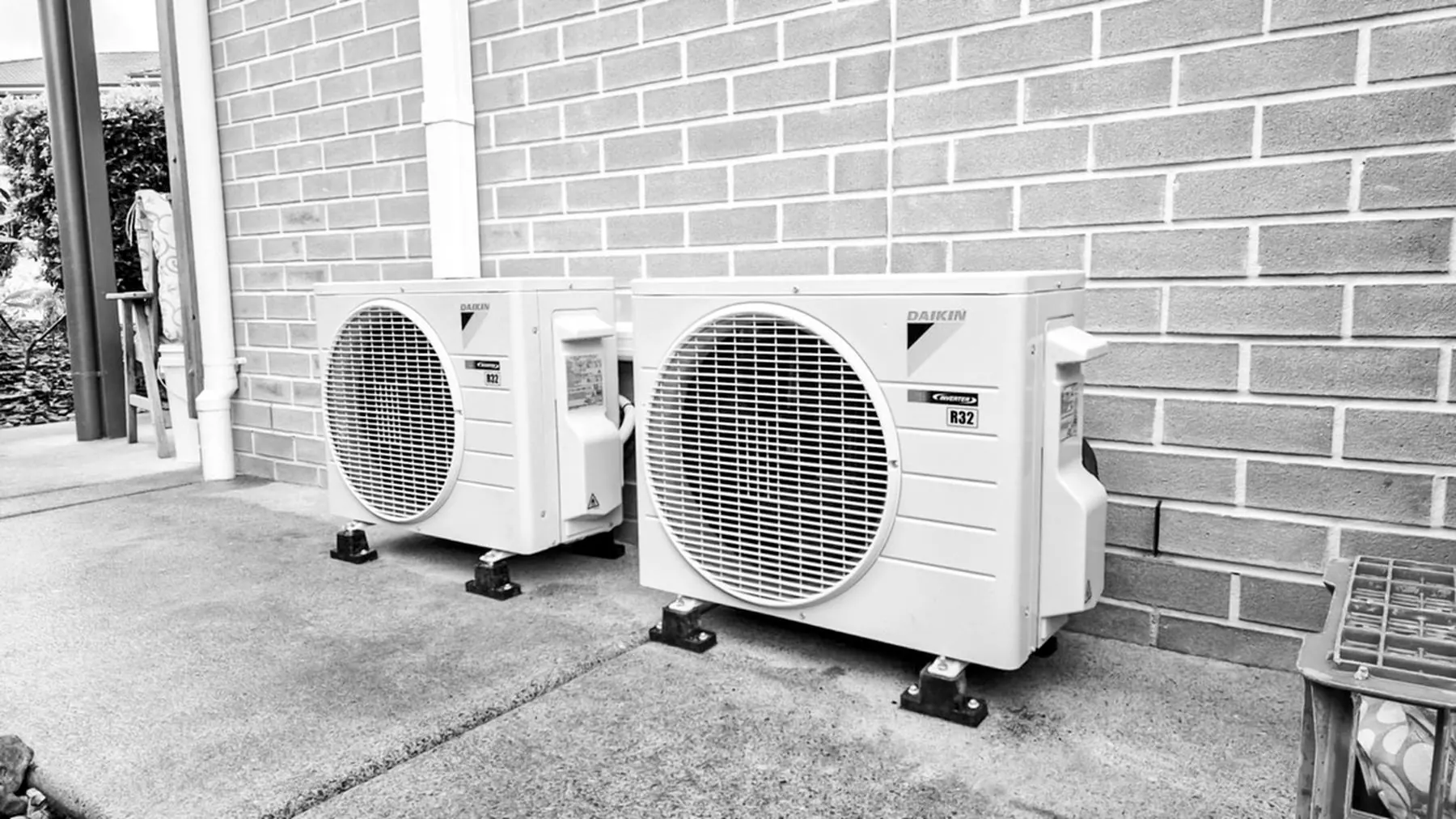 Two Daikin split system outdoor units installed beside a brick home